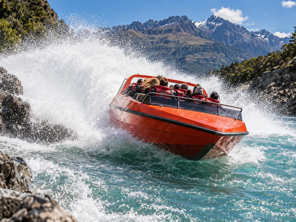 A jet boat throwing a large spray of water mid-turn on a fast river